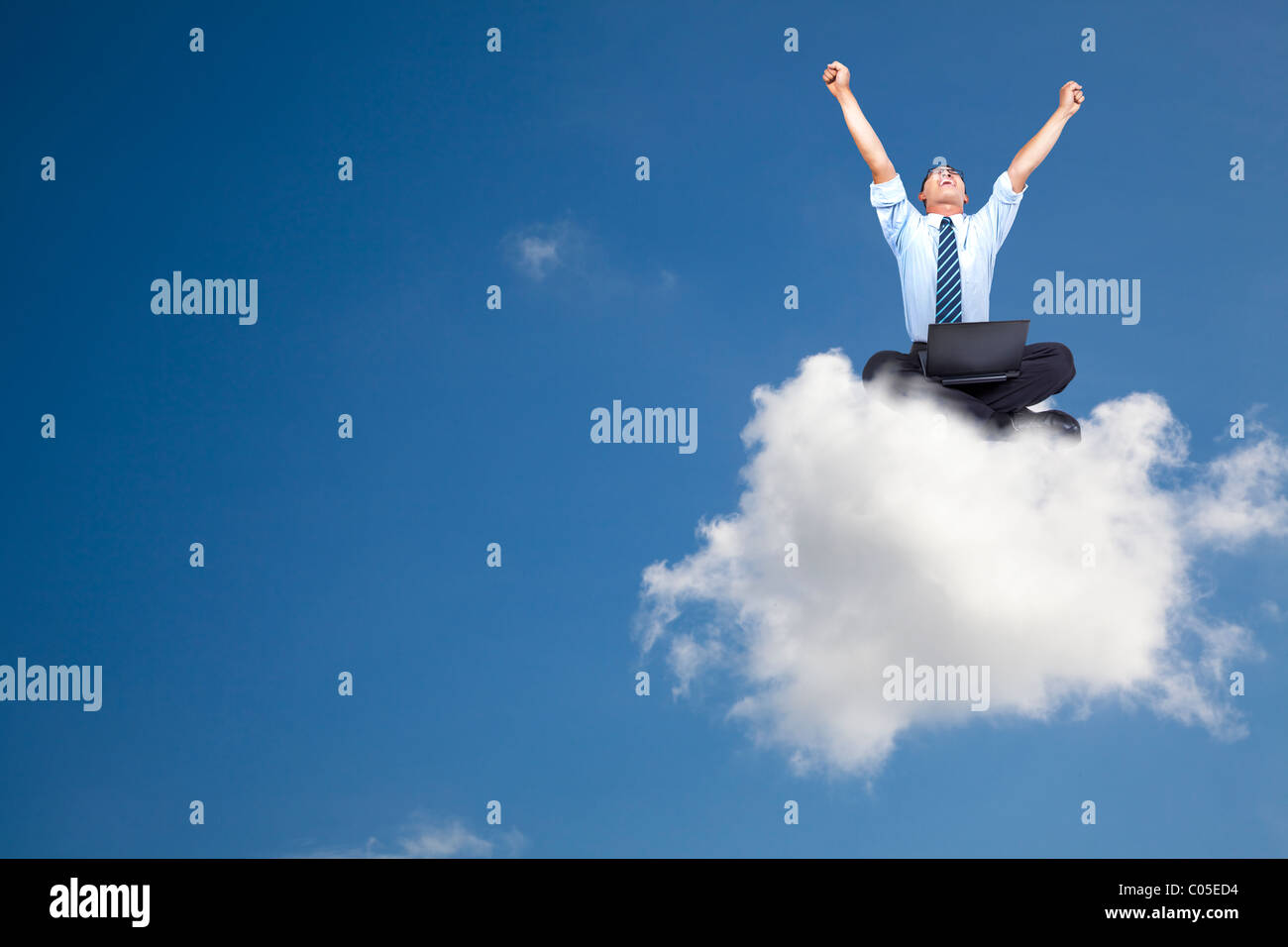 young businessman with computer sitting on the cloud Stock Photo