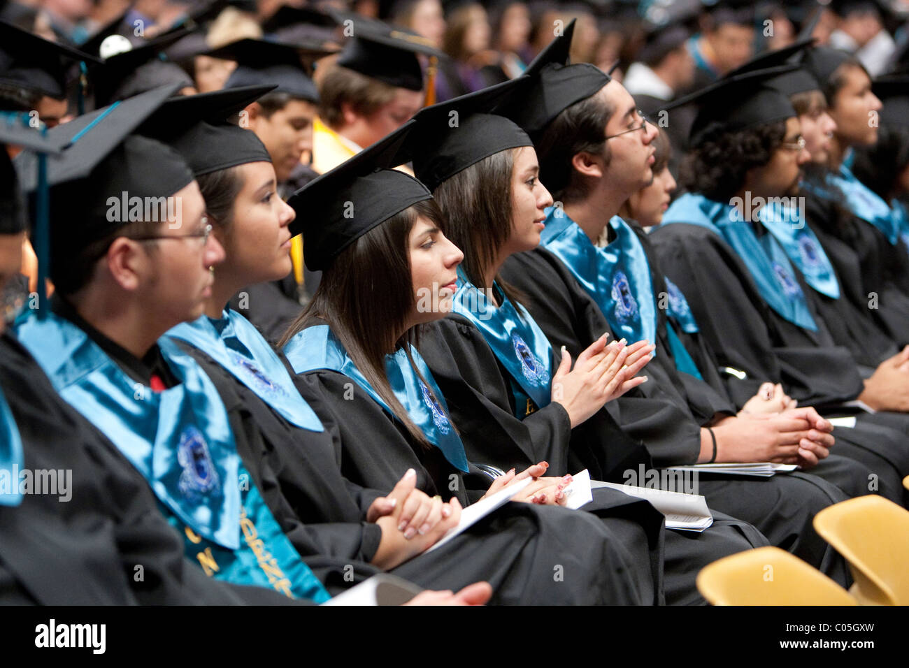 High school seniors in caps and gowns sitting in a row wait to receive