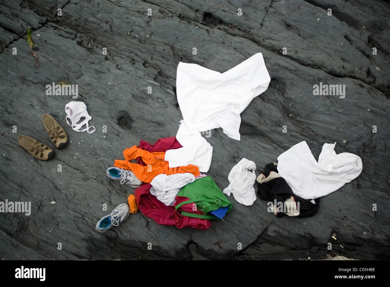 Some swimmers went skinny dipping in the ocean and left their clothes behind on the rocks ashore. Stock Photo