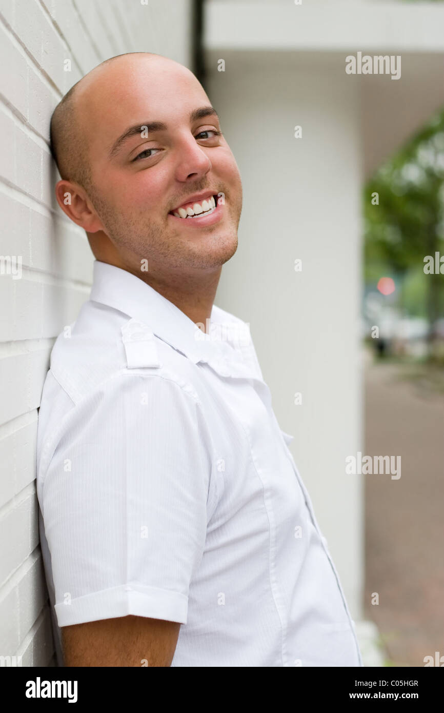 A young man with a casual pose leaning against a brick wall Stock Photo ...