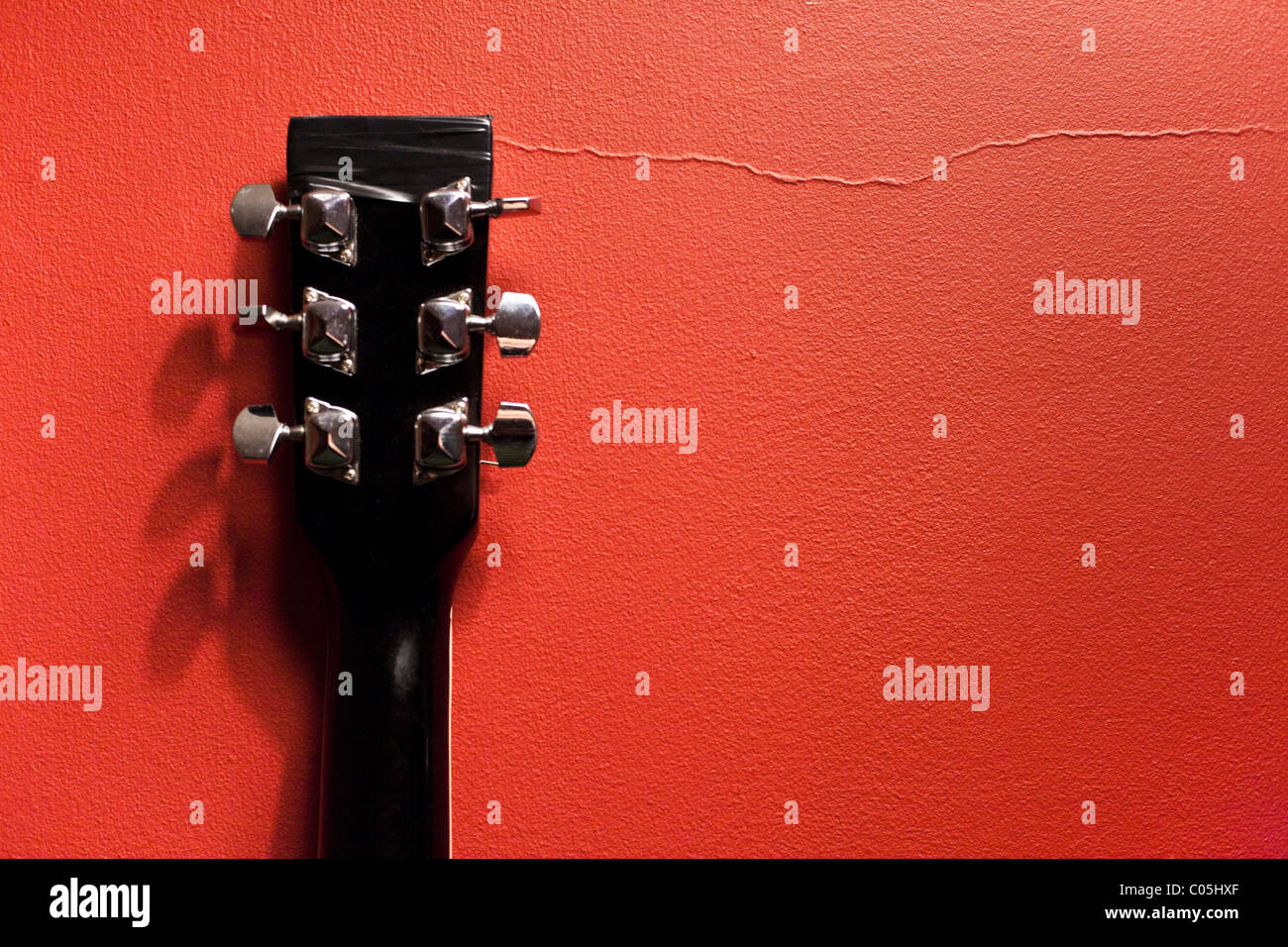 Classical guitar neck against red wall. Stock Photo