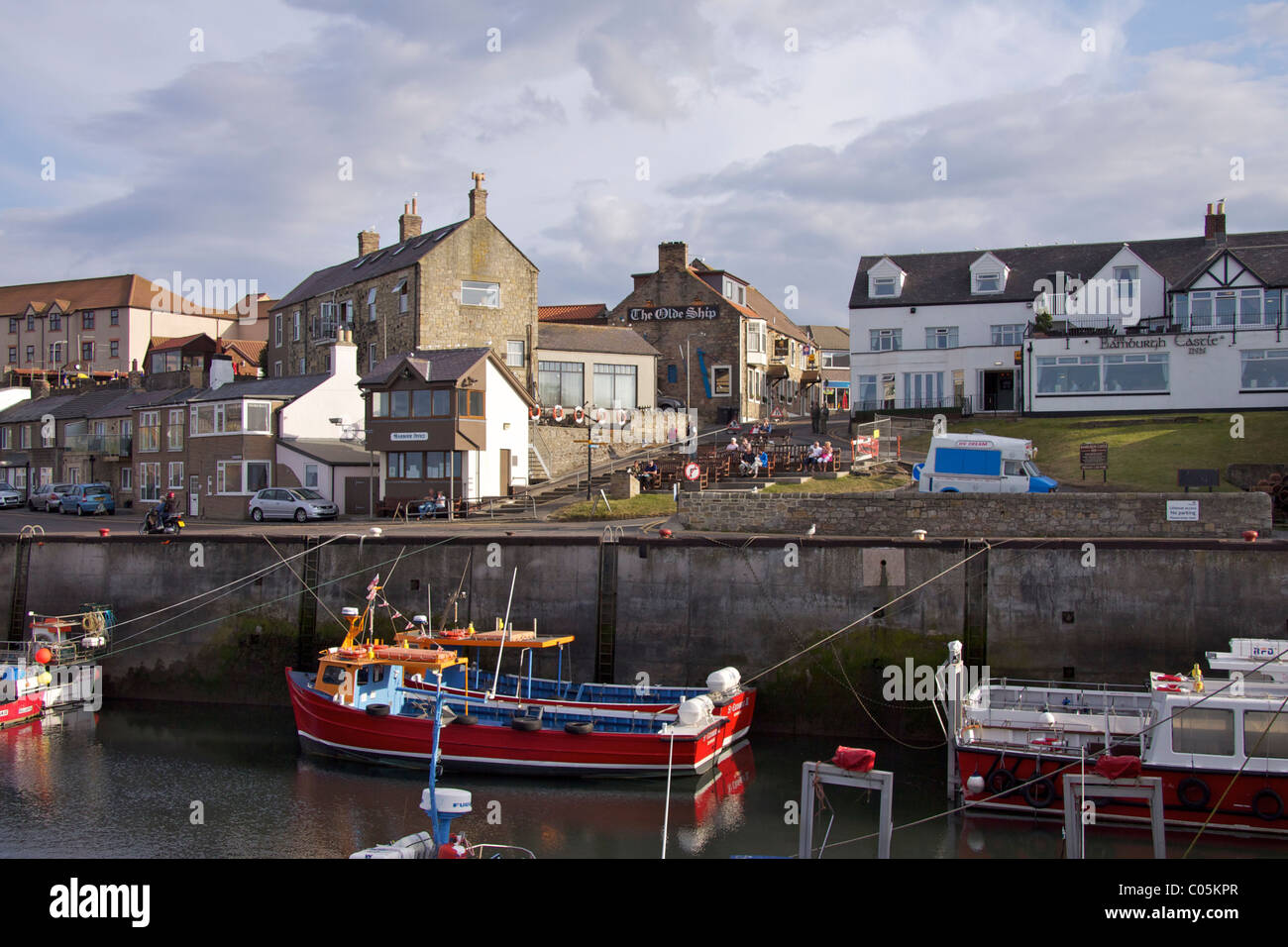 The harbour at Seahouses with the 'Bamburgh Castle' and 'Olde Ship' Inn on the quayside with boats moored in the harbour Stock Photo