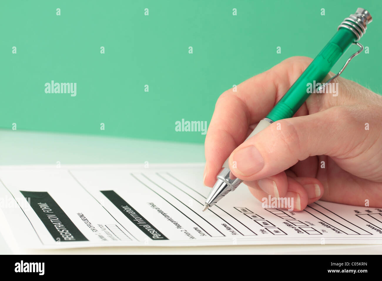 Green Themed Pen in Hand Completing Form Stock Photo - Alamy