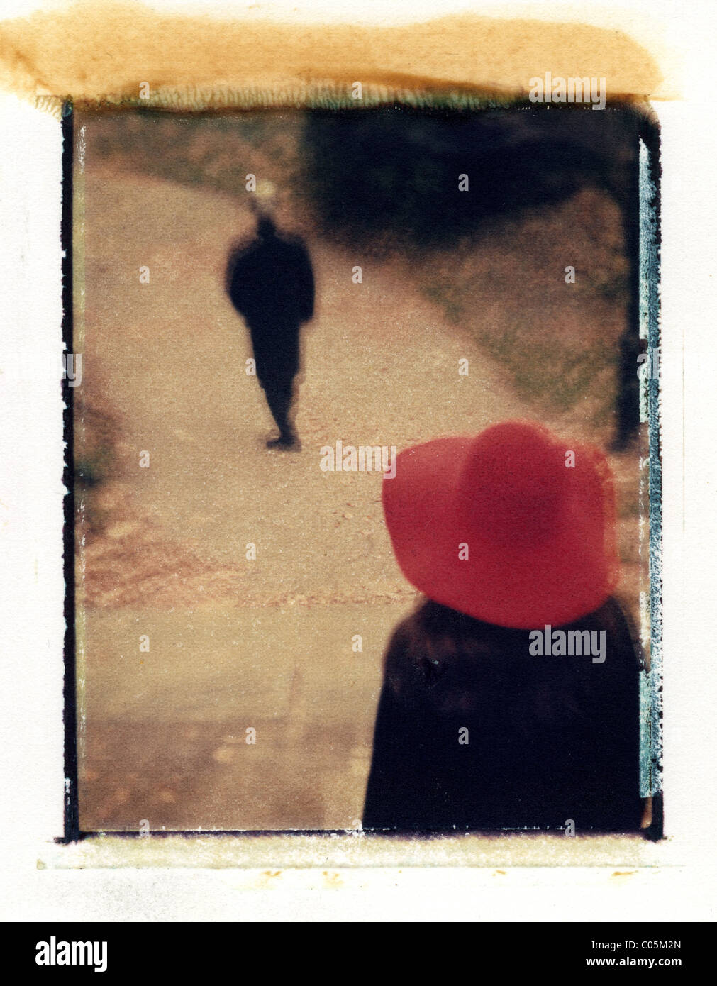 a women in red hat following a man in black from behind Stock Photo