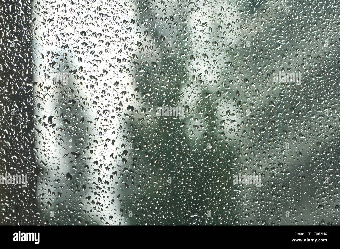 Rain drops on a window pane, blurry buildings in the back Stock Photo Alamy