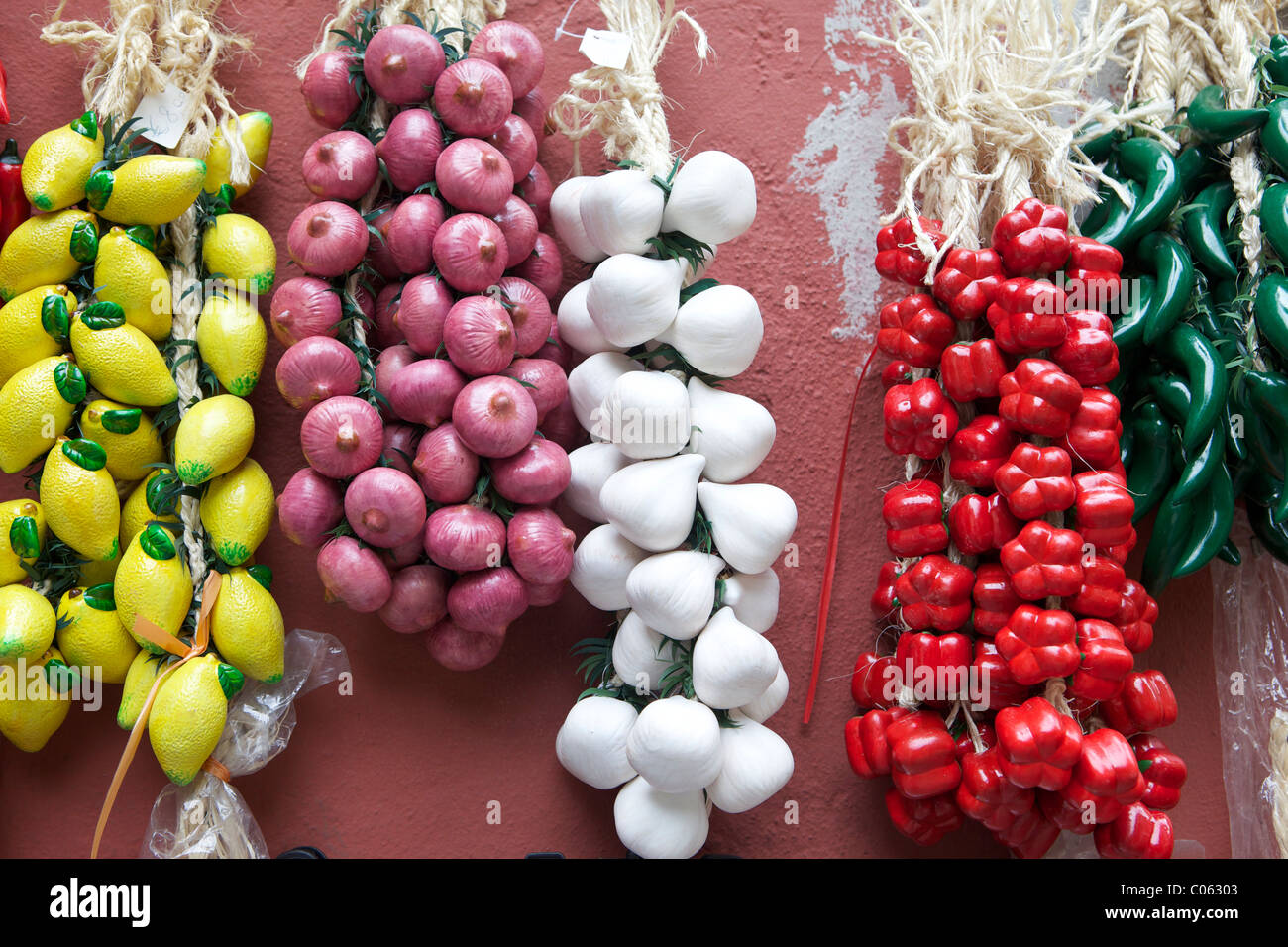 Freshly picked Lemons, Onions, Garlic, Red Peppers and Green Chillis hanging on the vine, for sale outside a store in Italy. A colorful display. Stock Photo