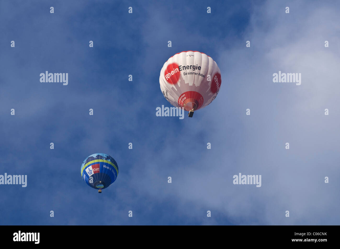 Two hot-air balloons, Klett Verlag and Rheinenergie, in front of a cloudy sky Stock Photo