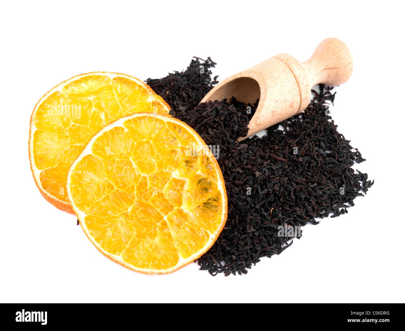 Dry aromatic black tea leavs with wooden shovel and orange on white