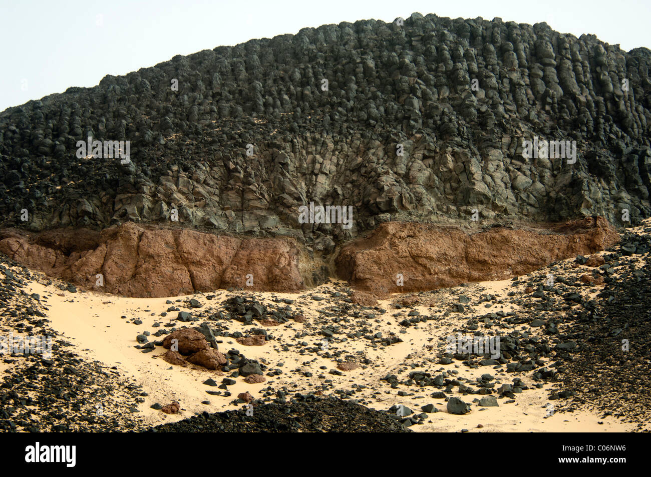 The Black Desert of Western Egypt-top layer of basalt rock sitting on top a layer of softer soil baked by the heat Stock Photo