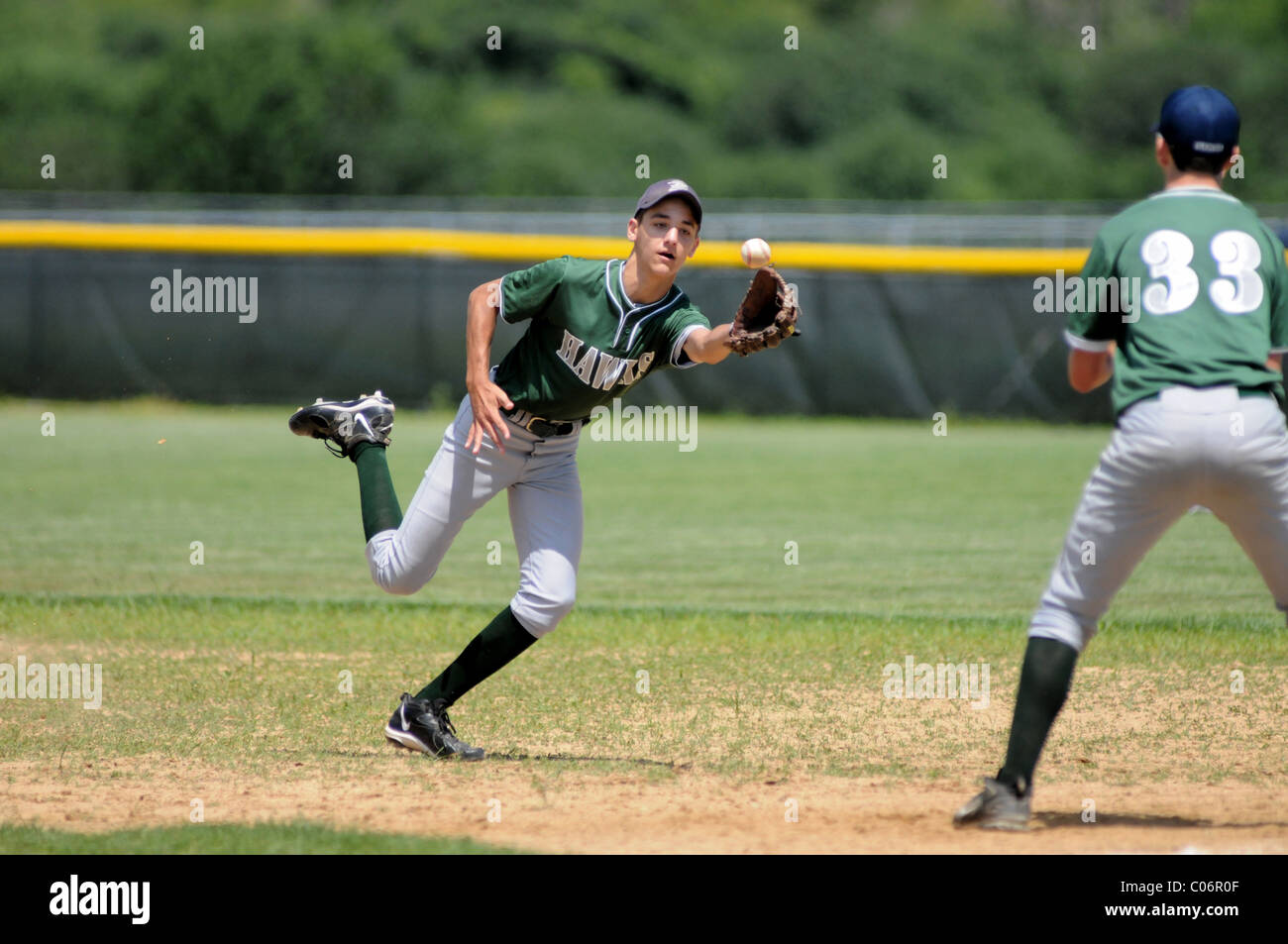 second baseman uses a glove originated shovel pass to retire a runner at first base during a high school baseball game. USA. Stock Photo