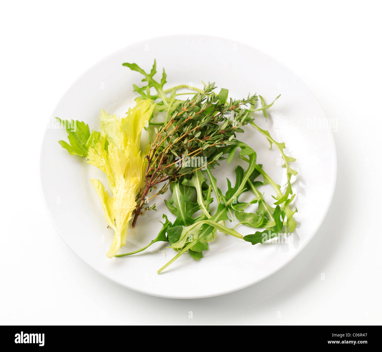Sprigs of thyme and salad greens on a plate Stock Photo