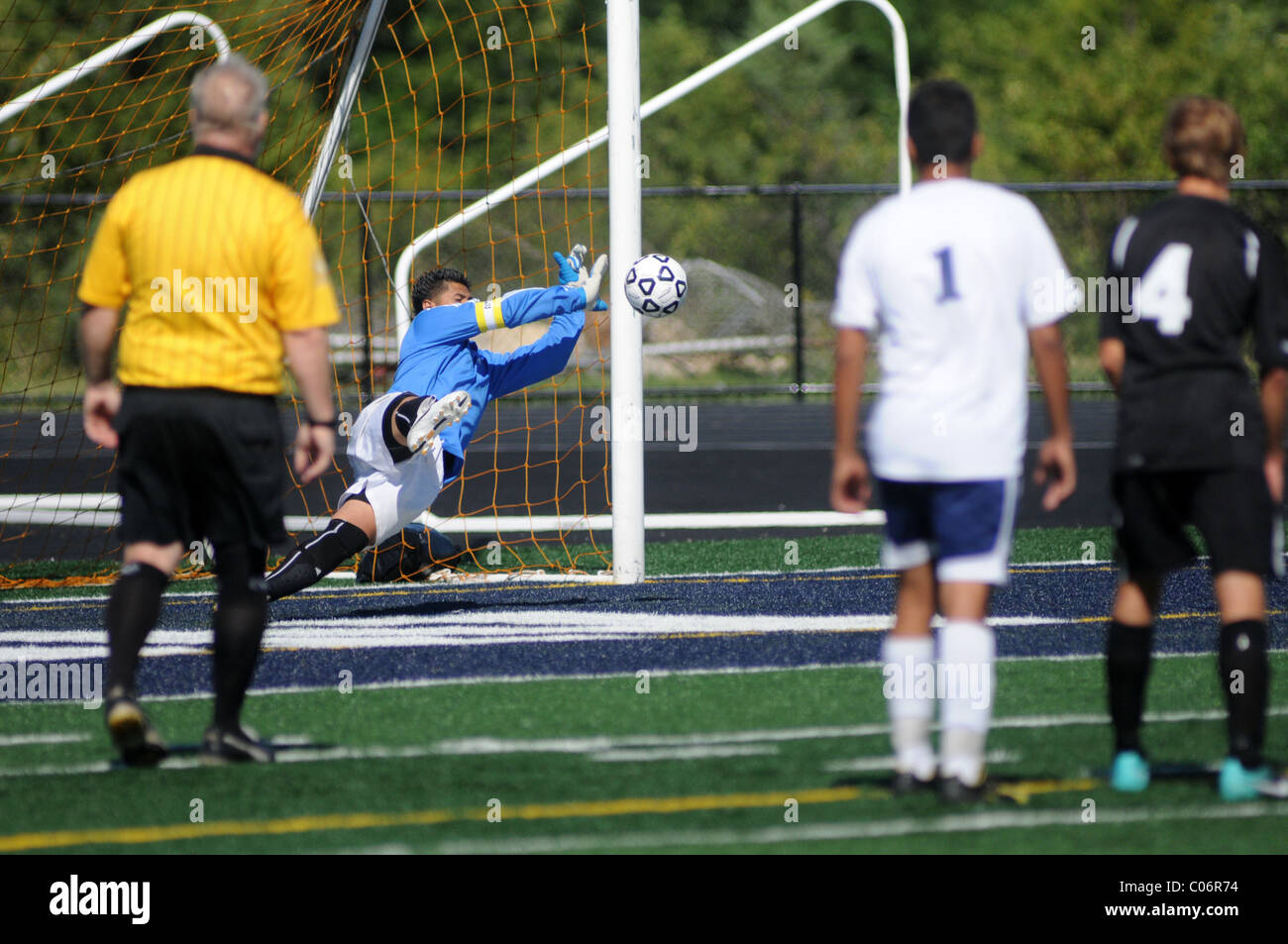 Official and players look on as high school goal keeper makes an