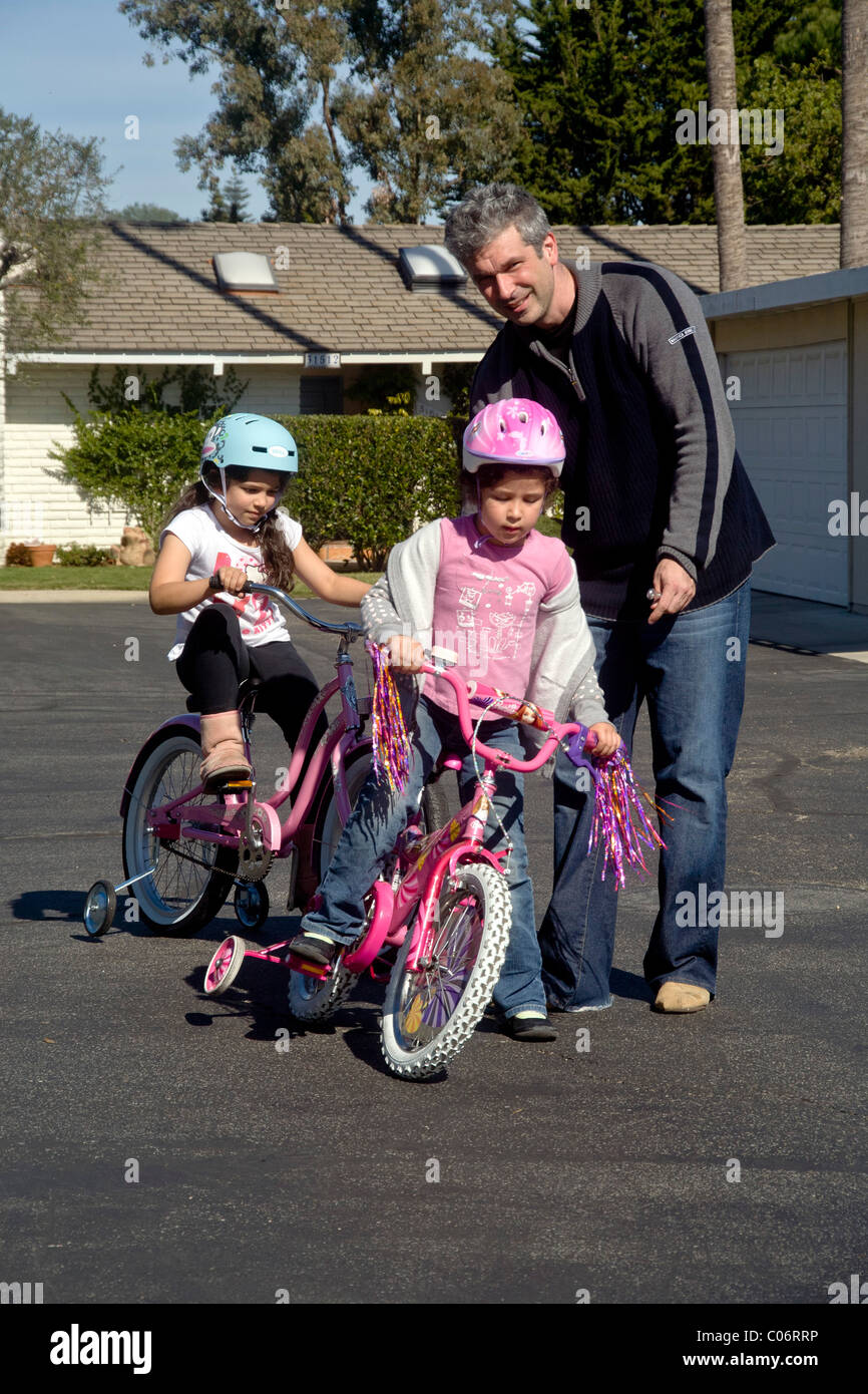 Dad helps his five year old daughter learn to ride her new bicycle with