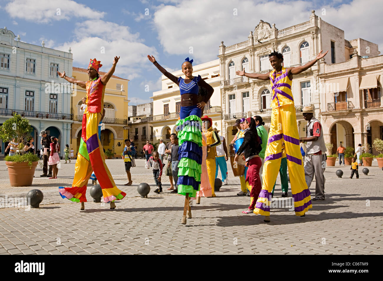 A group of street artist or performers parading on stilts walk through the streets of Havana, Cuba in bright colourful costumes Stock Photo