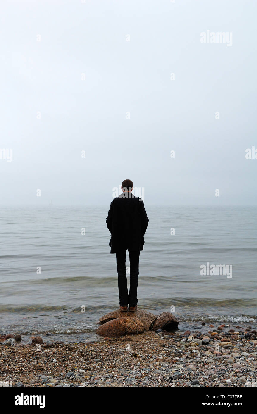 Young man standing in inclement weather on the Baltic Sea, Gross Schwansee, Mecklenburg-Western Pomerania, Germany, Europe Stock Photo