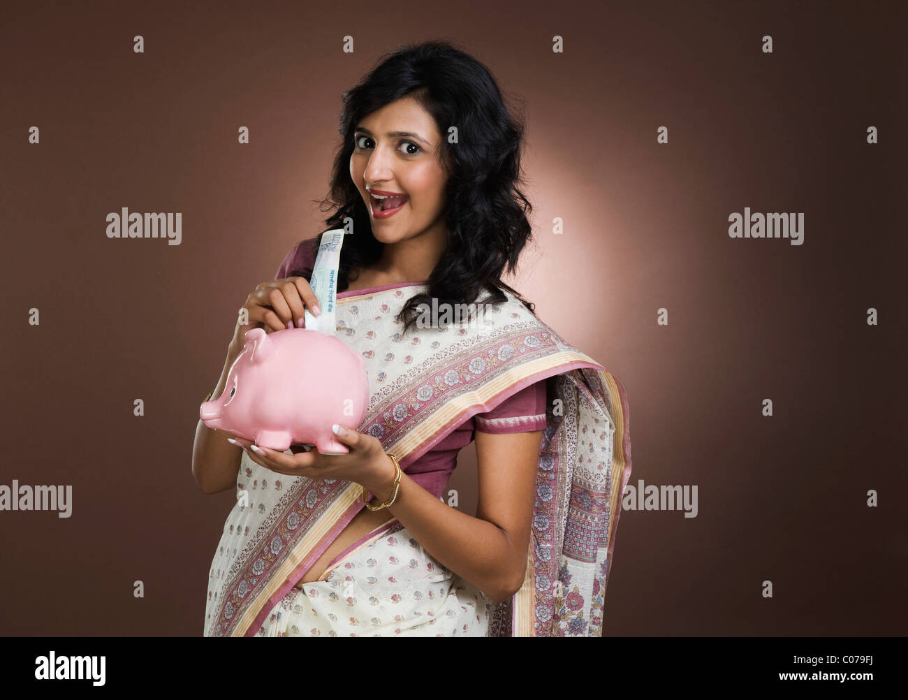 Woman putting a currency note into a piggy bank Stock Photo - Alamy