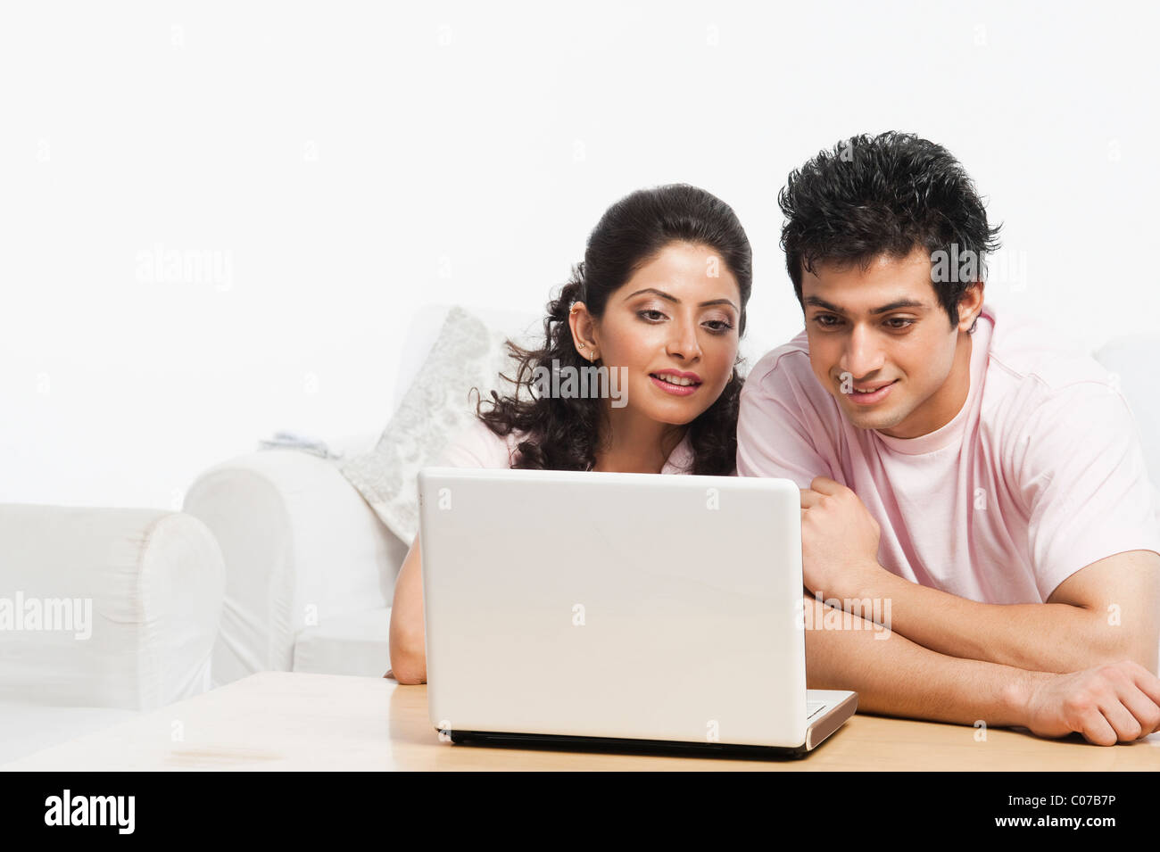 Couple sitting in a couch and using a laptop Stock Photo - Alamy