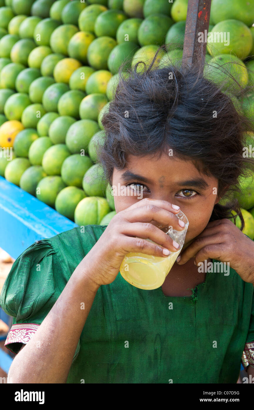 Young Indian street girl drinking fresh orange juice on an indian street, Andhra Pradesh, India Stock Photo