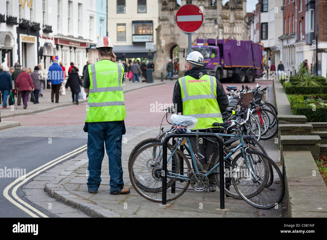 A workman in Hi-Viz jacket talks on his mobile phone while a colleague looks on. Stock Photo