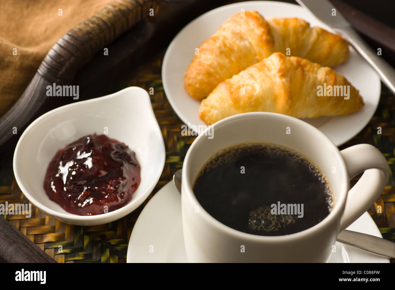 A tray with croissants, jam and a cup of hot black coffee Stock Photo