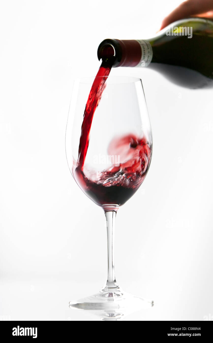 A glass of Red Wine being poured from the bottle on a white background. Stock Photo