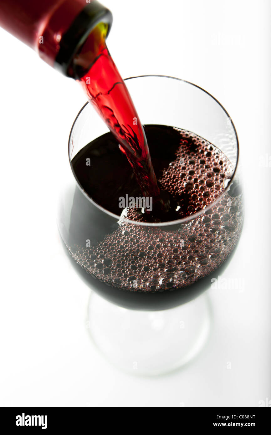 A glass of Red Wine being poured from the bottle on a white background. Stock Photo