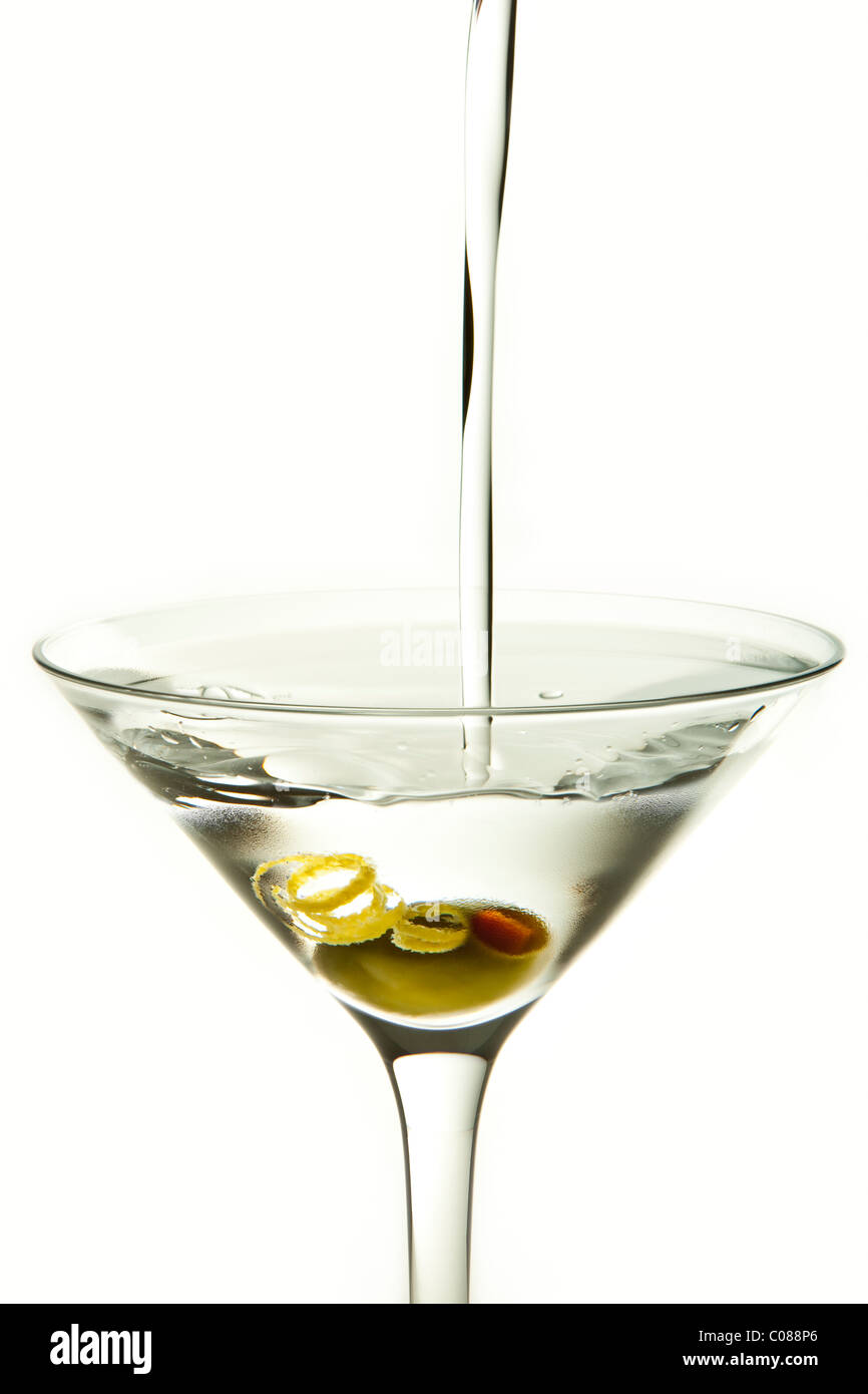 A glass of Martini Cocktail with Olive Garnish and pour on a white background. Stock Photo