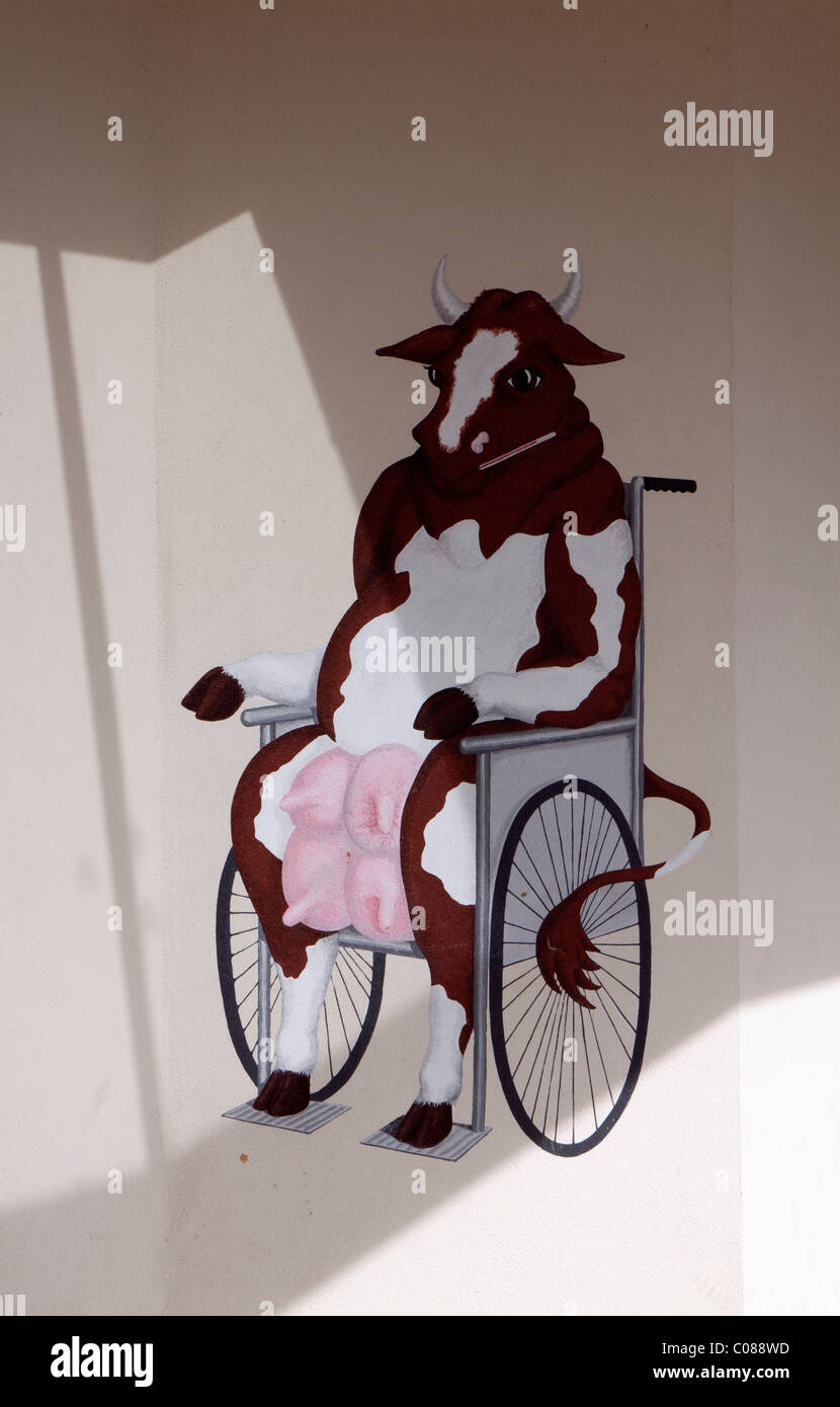 Comical cartoon of a cow in a wheelchair outside a cafe Stock Photo
