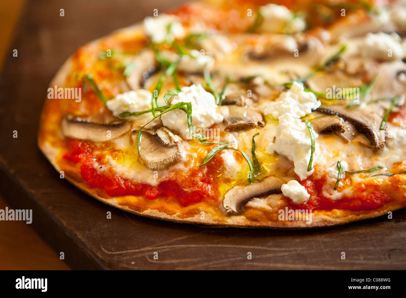 Thin and crispy crust Pizza with Mozzarella, Mushrooms, Goat Cheese and Basil prepared by Gianni Scappin, Chef/Owner of Cucina W Stock Photo