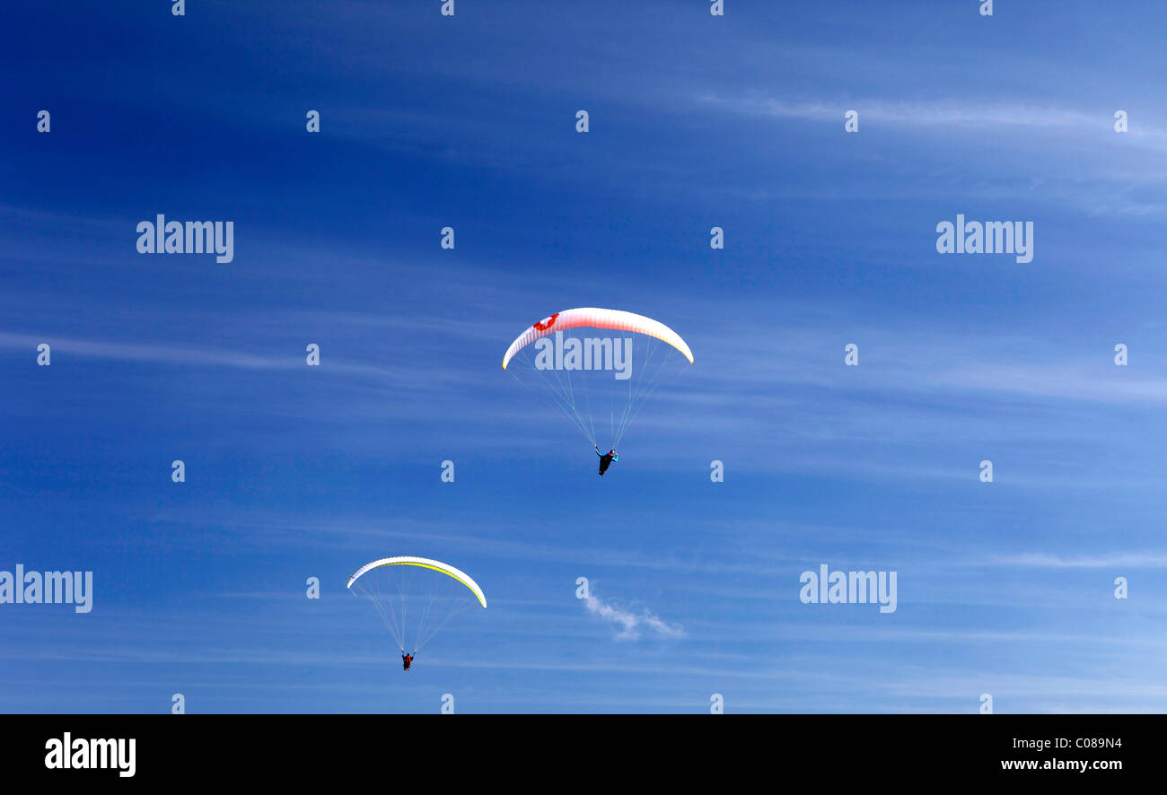 Paragliders taking part in extreme sports, jumping and flying from Monte Baldo mountain range near Lake Garda in Italy. Stock Photo