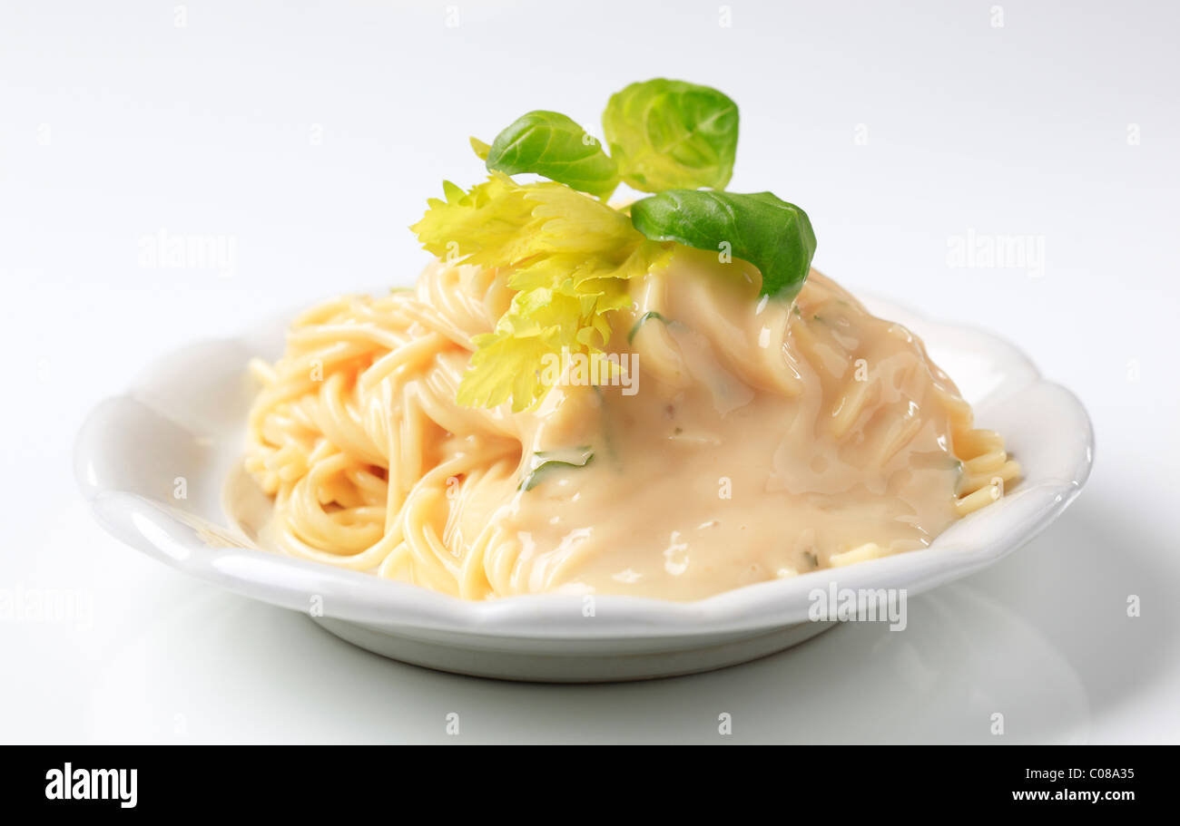 Spaghetti with creamy sauce garnished with fresh basil Stock Photo