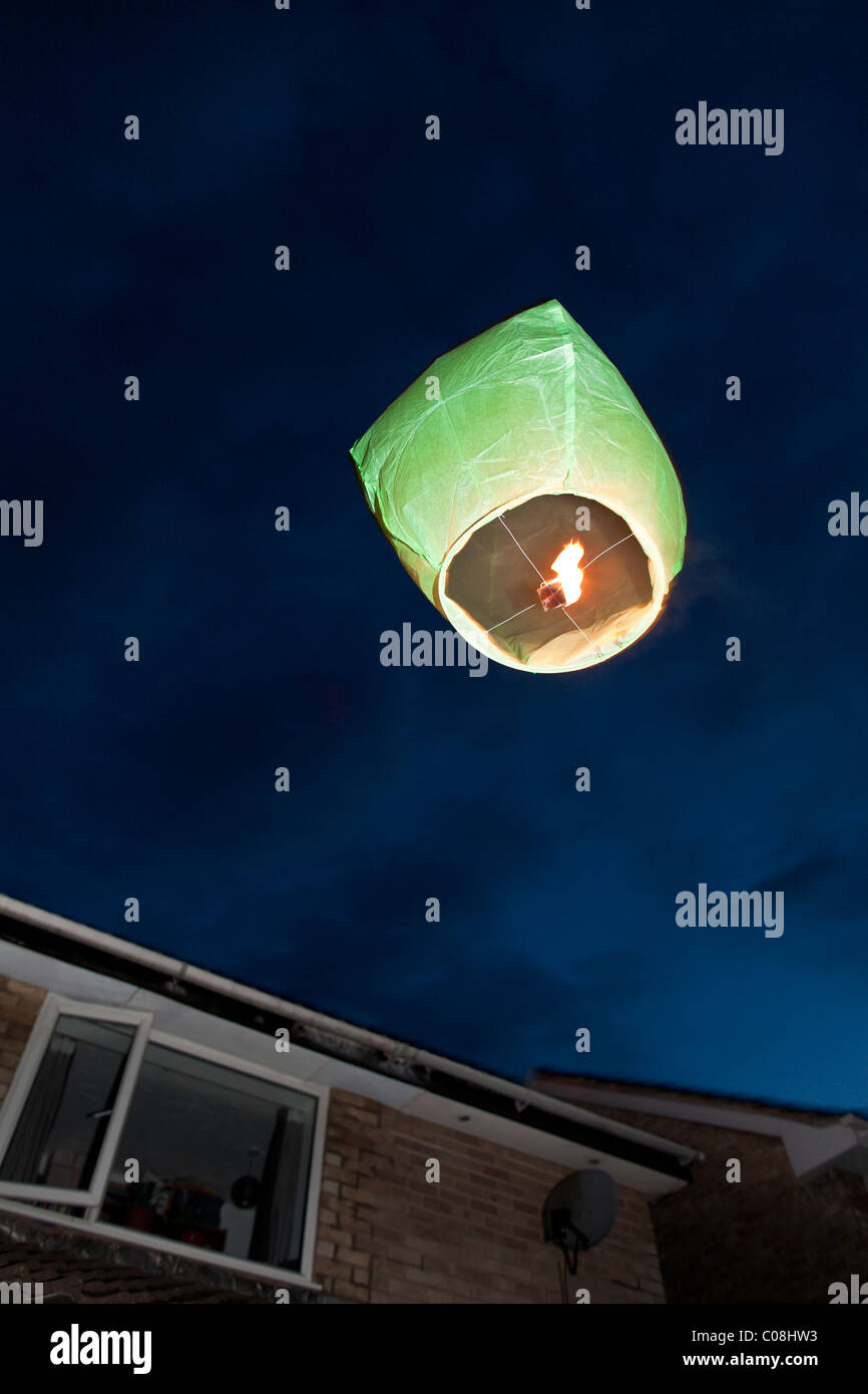 Chinese paper sky lantern afloat on a still evening with flame burning bright. Stock Photo