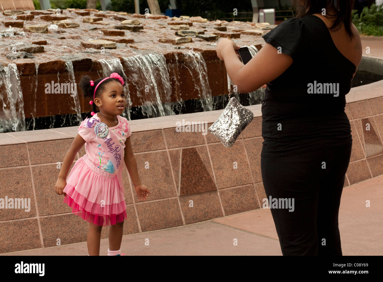 Young African American girl poses in front of Epcot fountain at Disney World, Orlando, Florida. Stock Photo