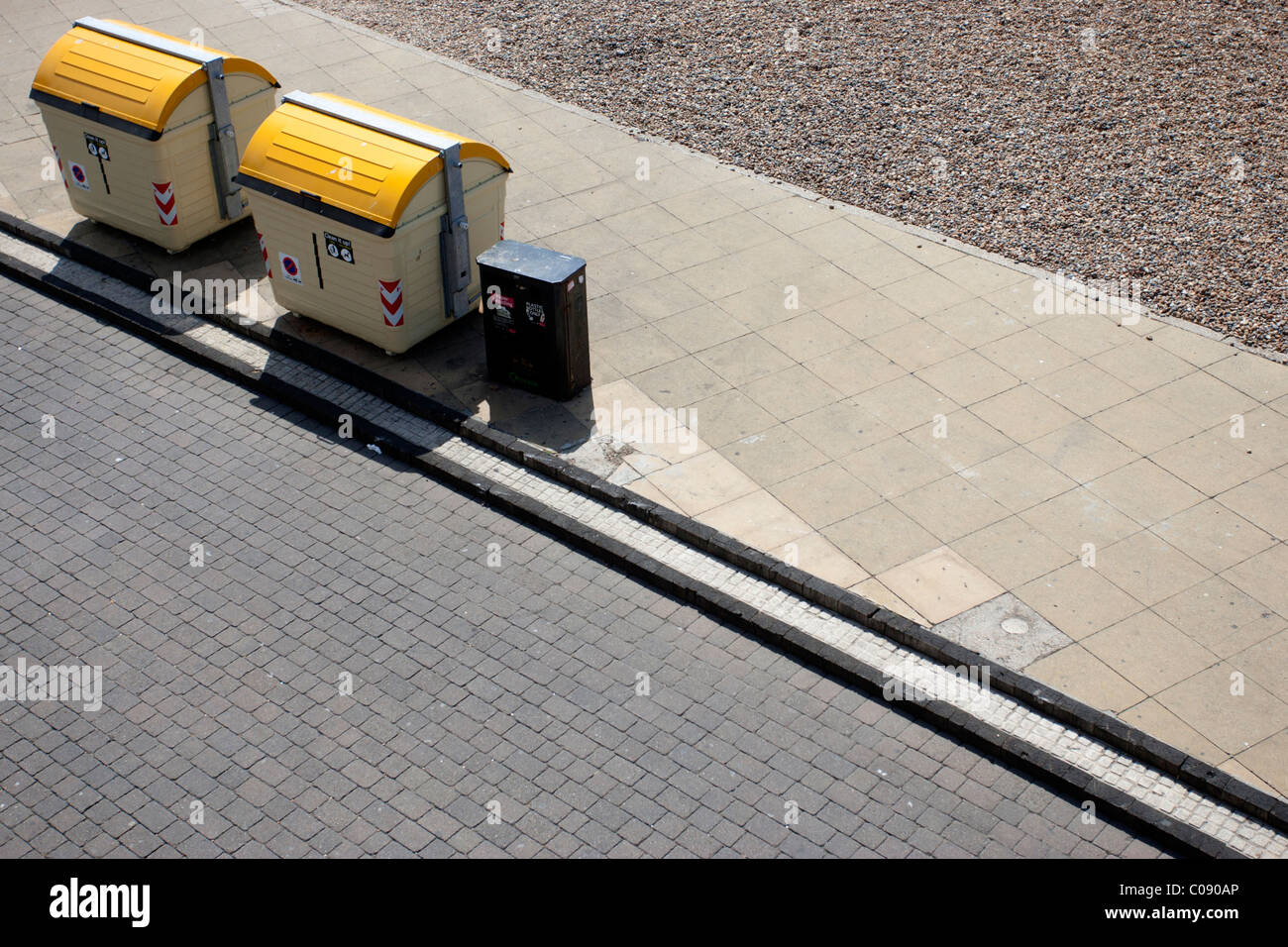 Two yellow public waste bins and a little black bin on the seafront in