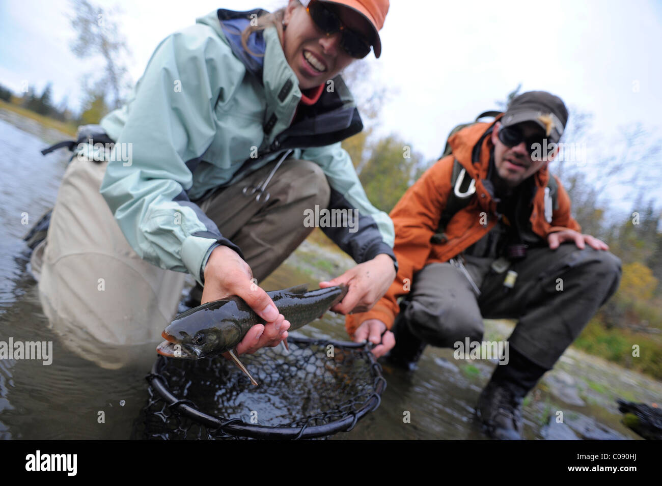 Man and woman kneeling in water to show off a Dolly Varden char caught in Deep Creek, Kenai Peninsula, Southcentral Alaska Stock Photo