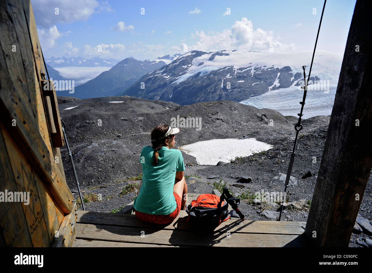 Female backpacker enjoys the view from an alpine hut along the Harding Icefield trail, Kenai Fjords National Park, Alaska Stock Photo