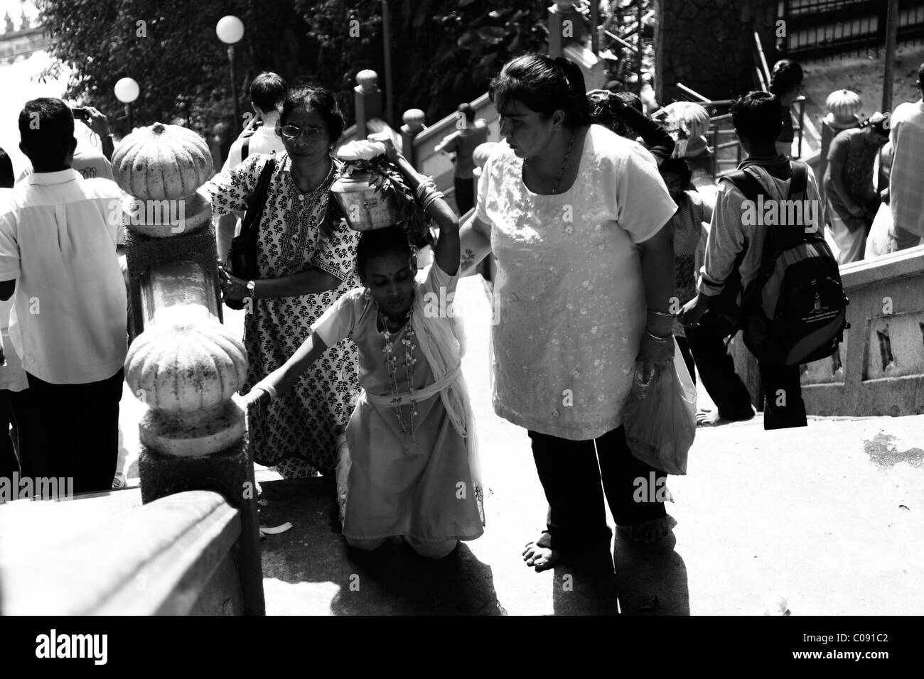 Hindu woman kneeling as part of milk offering ritual during Thaipusam Stock Photo