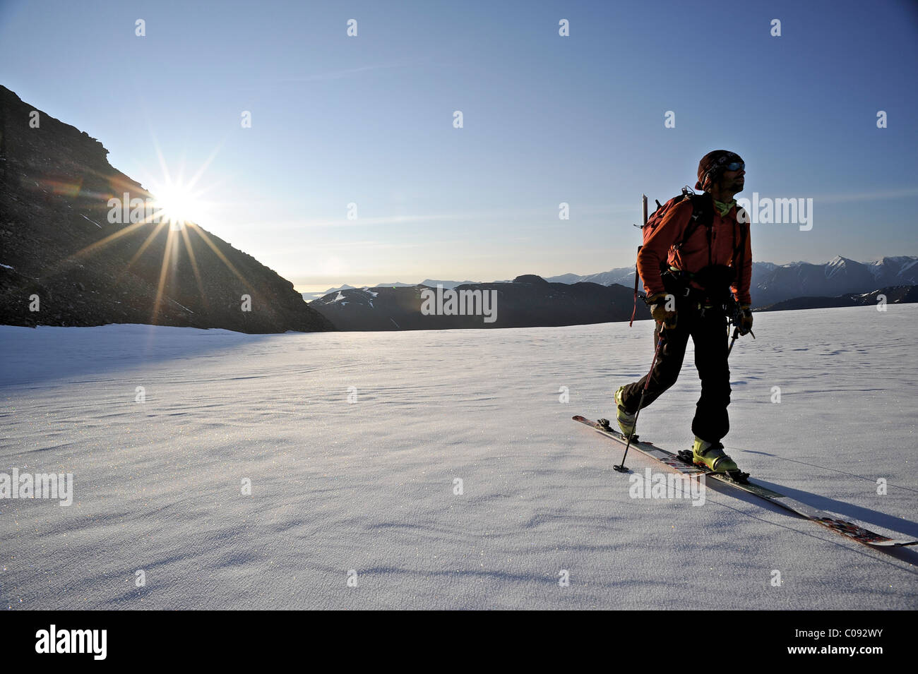 Backcountry skier makes an early morning ascent of the north side of Mt. Chamberlin, Brooks Range, ANWR, Arctic Alaska, Summer Stock Photo