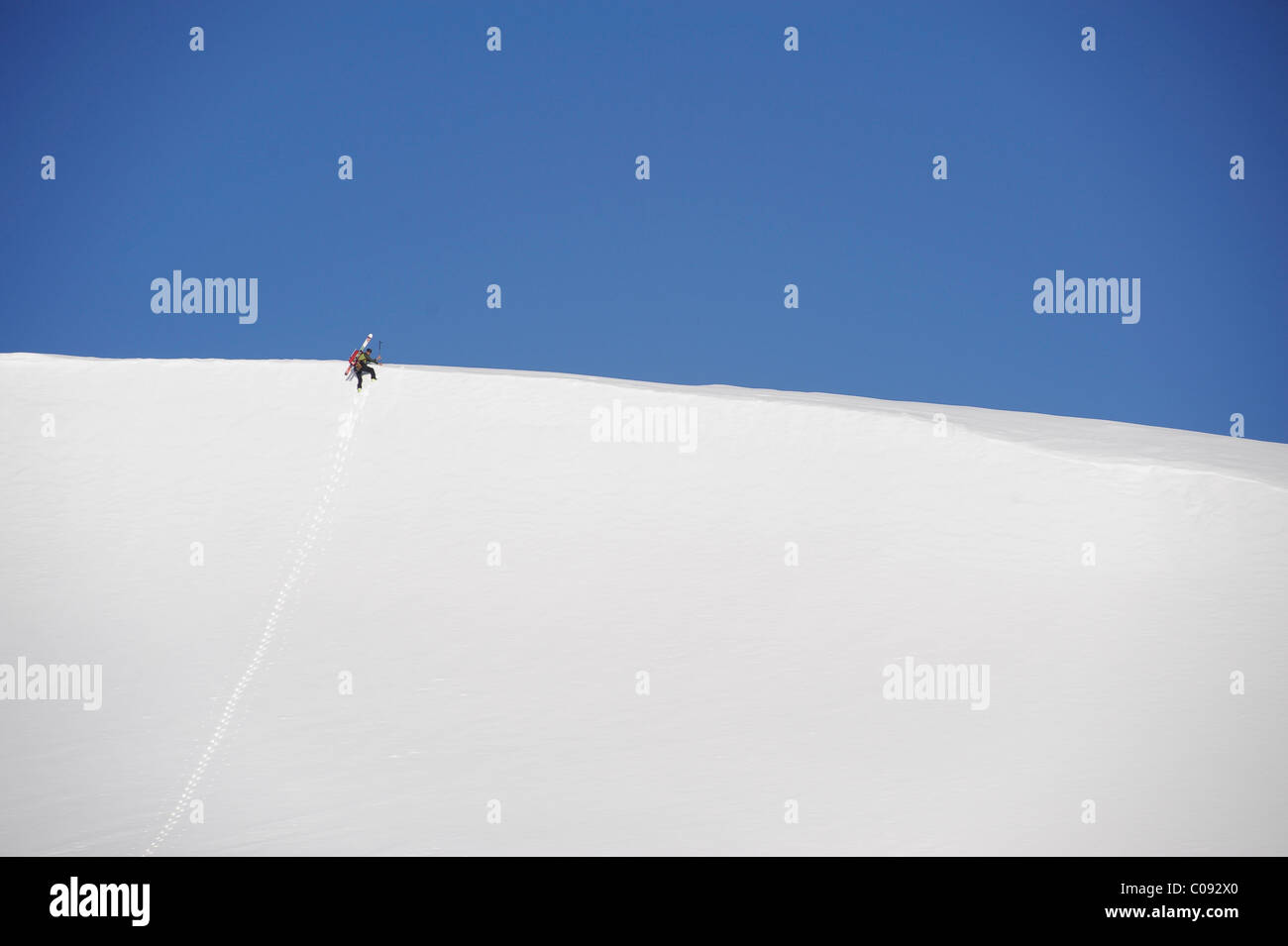 Backcountry skier makes an early morning ascent of the north side of Mt. Chamberlin, Brooks Range, ANWR, Arctic Alaska, Summer Stock Photo
