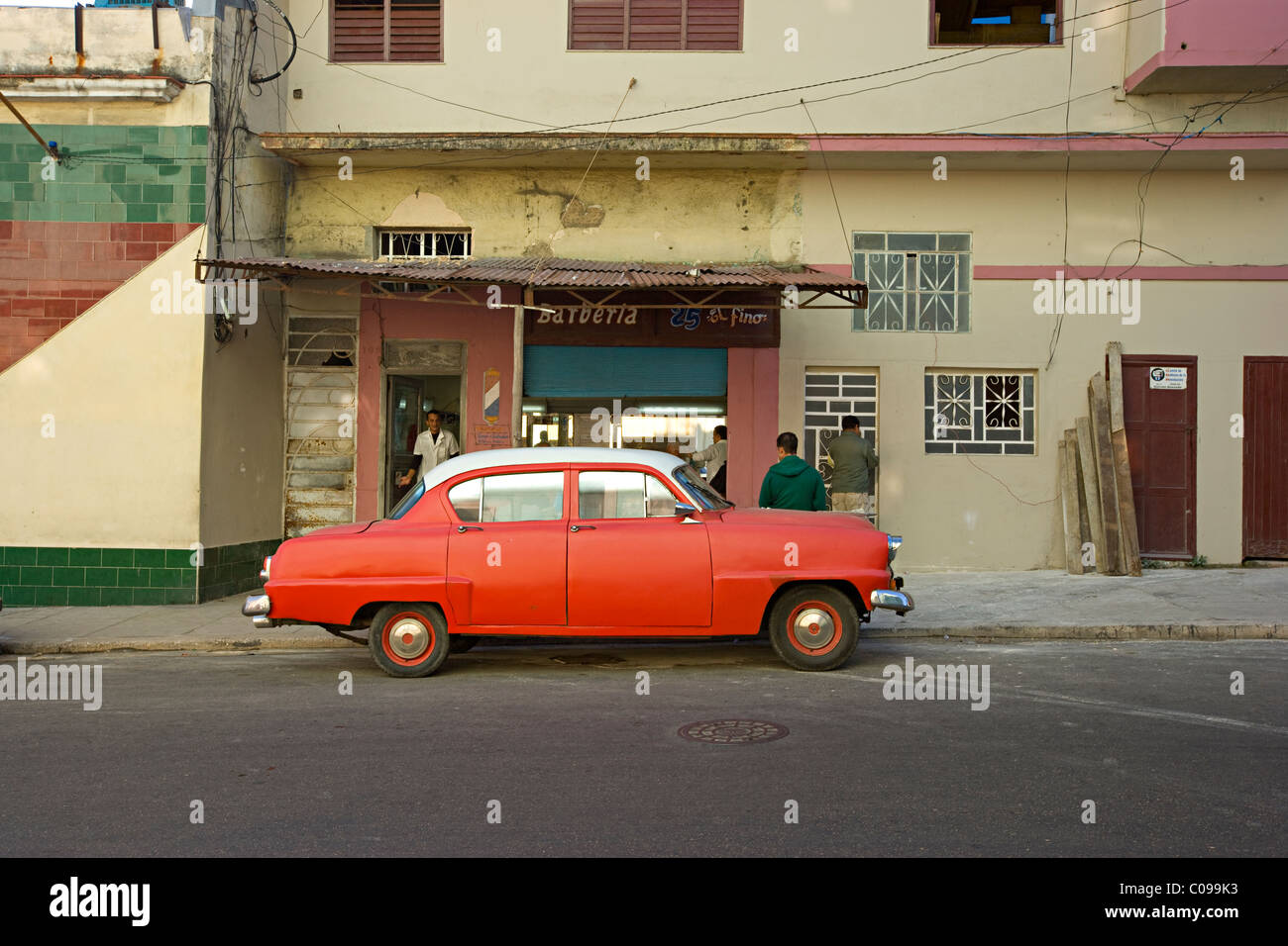 An old American 1950s red automobile parked outside a barbers in a street in Havana  Cuba Stock Photo