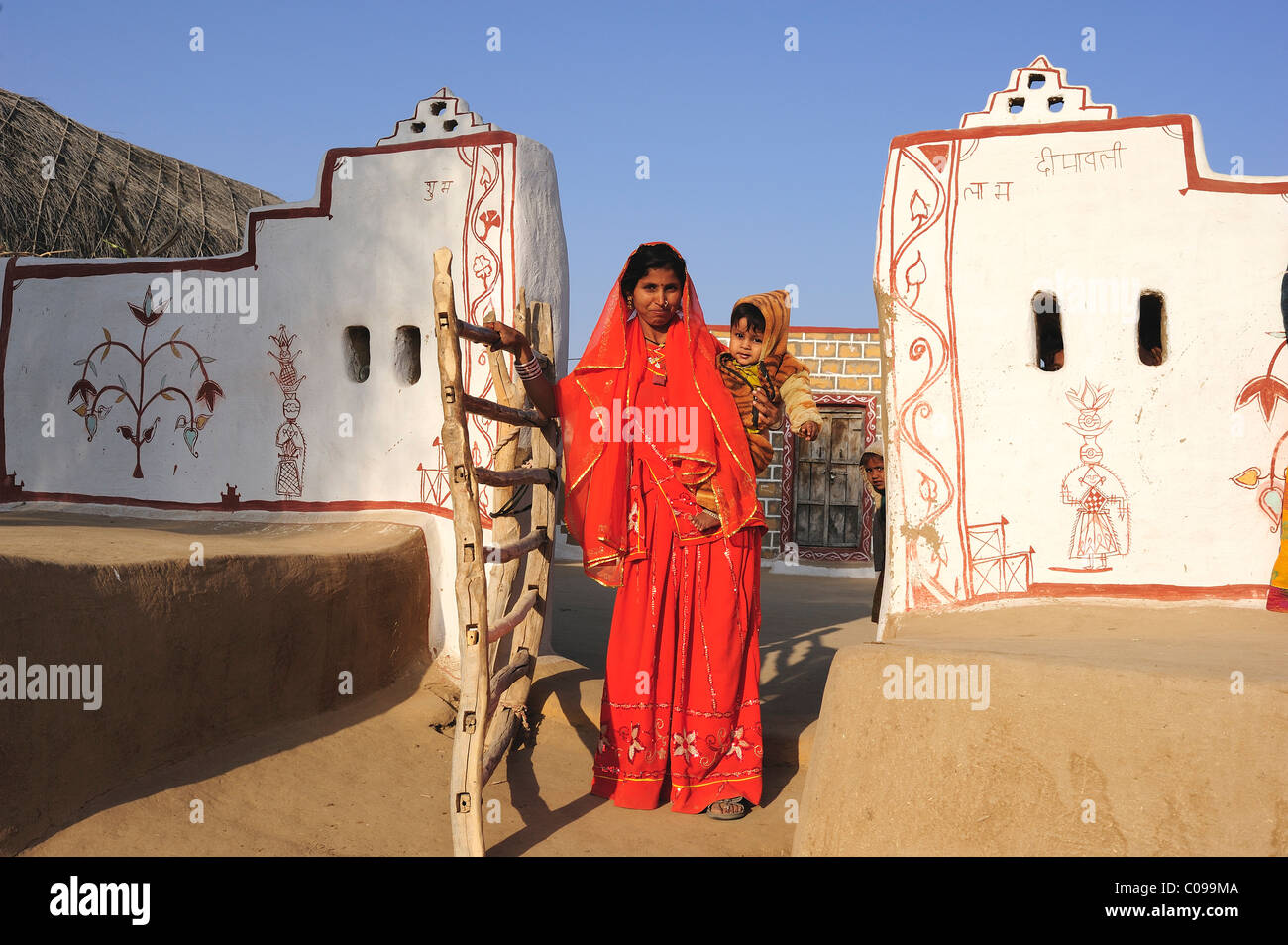 Woman in a sari with a toddler, traditionally painted entrance to a courtyard, Thar Desert, Rajasthan, North India, India, Asia Stock Photo