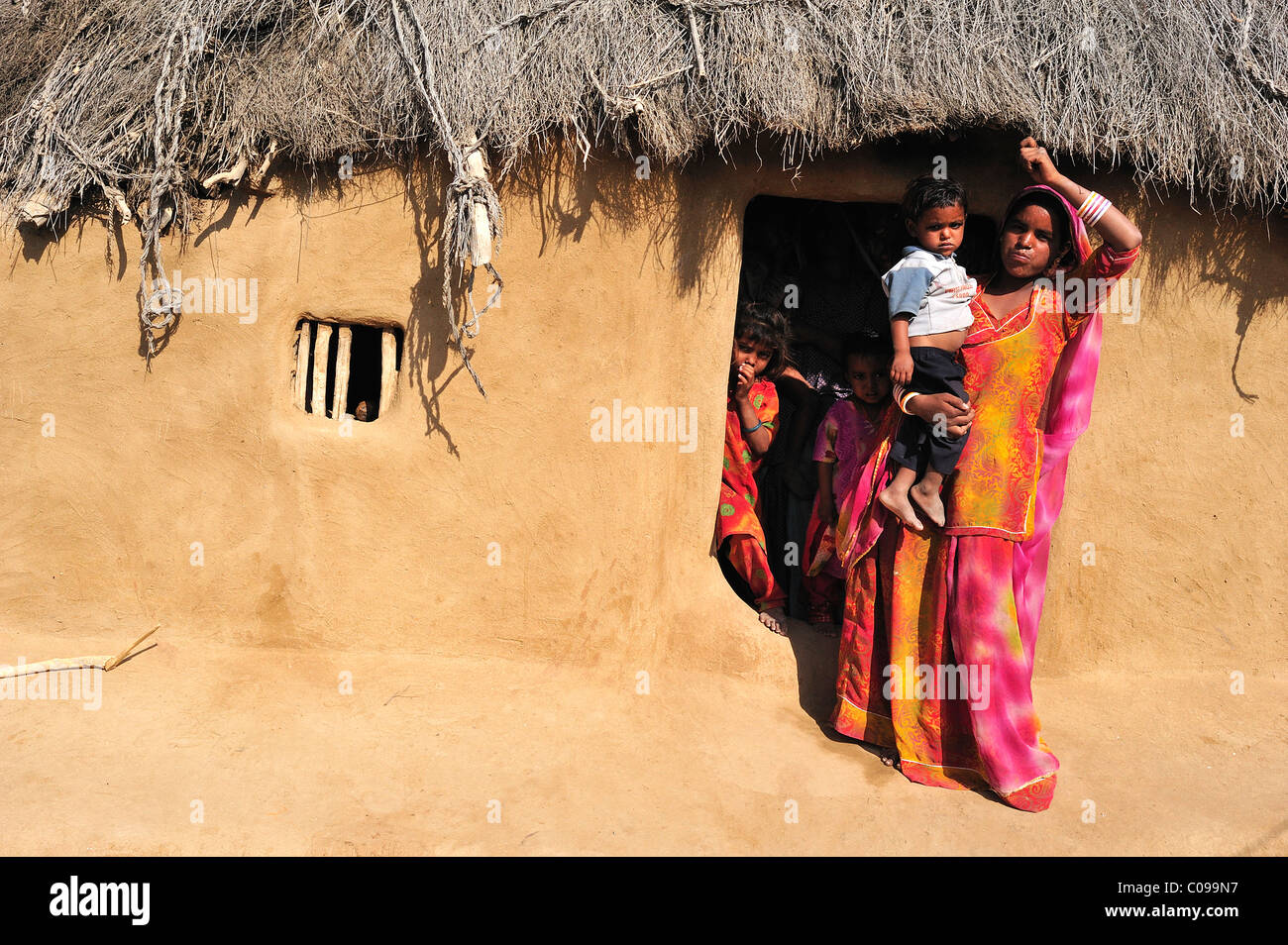 Woman in a sari with a toddler at the entrance to her house, Thar Desert, Rajasthan, North India, India, Asia Stock Photo