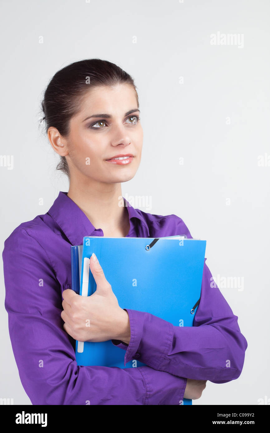 Pretty young brunette woman holding colorful plastic folders Stock Photo