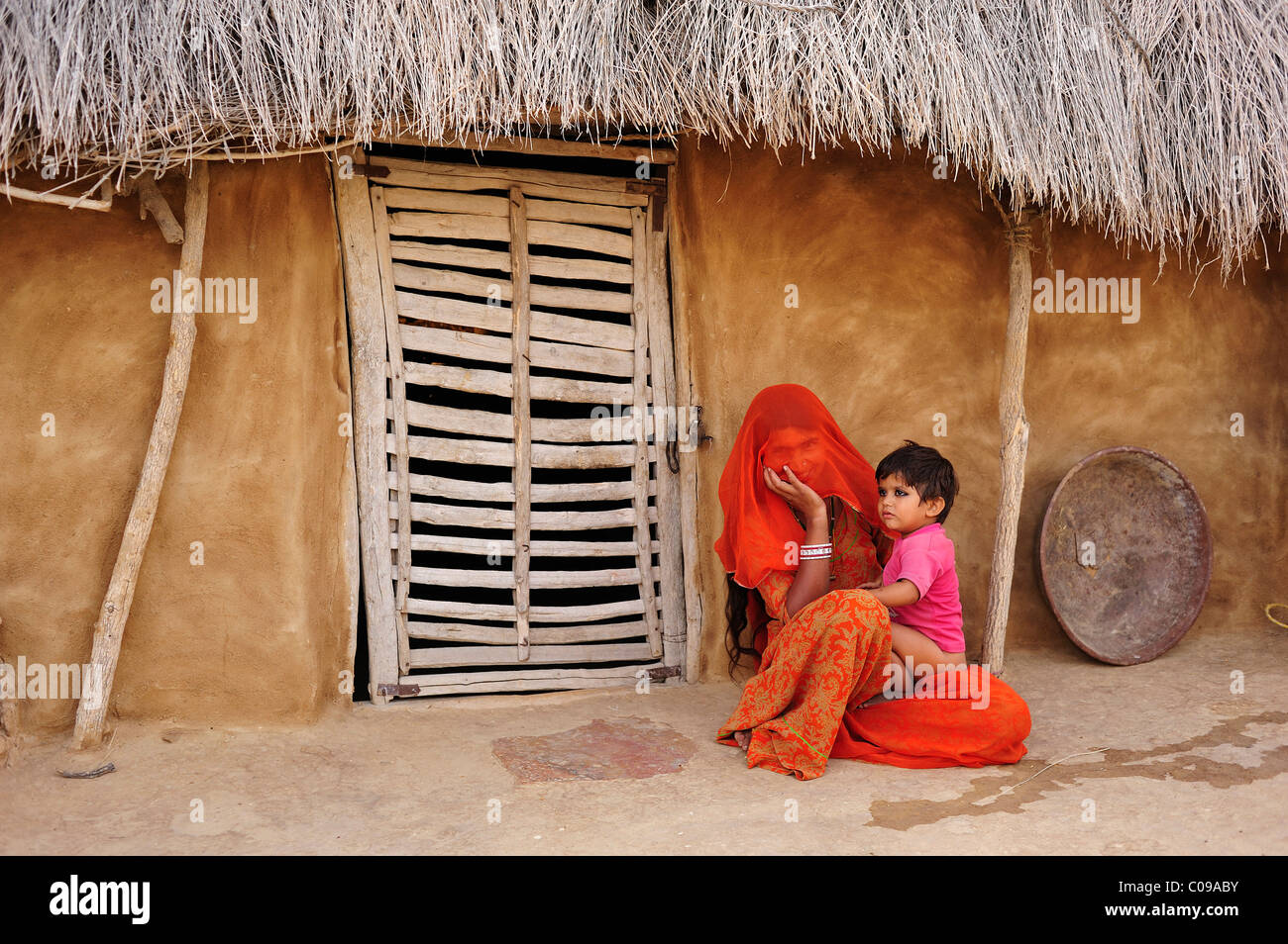 Mother with her child in front of house entrance, Thar Desert, Rajasthan, India, Asia Stock Photo