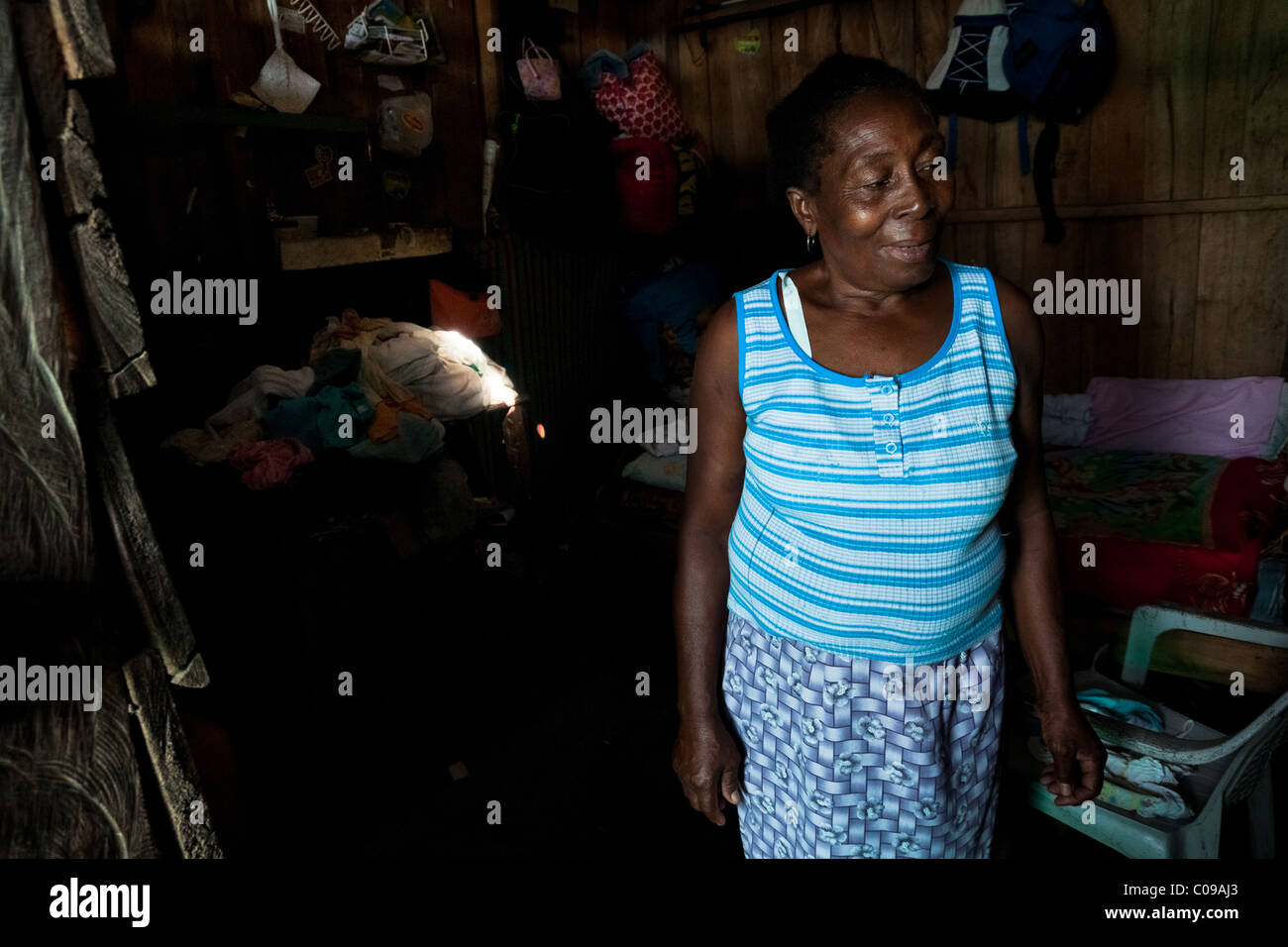 A Colombian woman, a shellfish picker, stands inside her wooden house in a stilt house area close to Tumaco, Colombia. Stock Photo