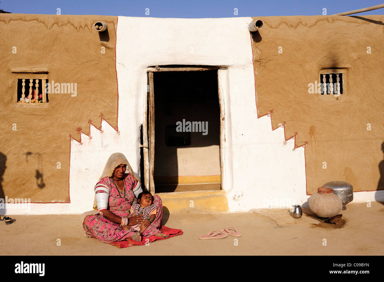 A mother with her child in front of the painted entrance to her house, Thar Desert, Rajasthan, India, Asia Stock Photo