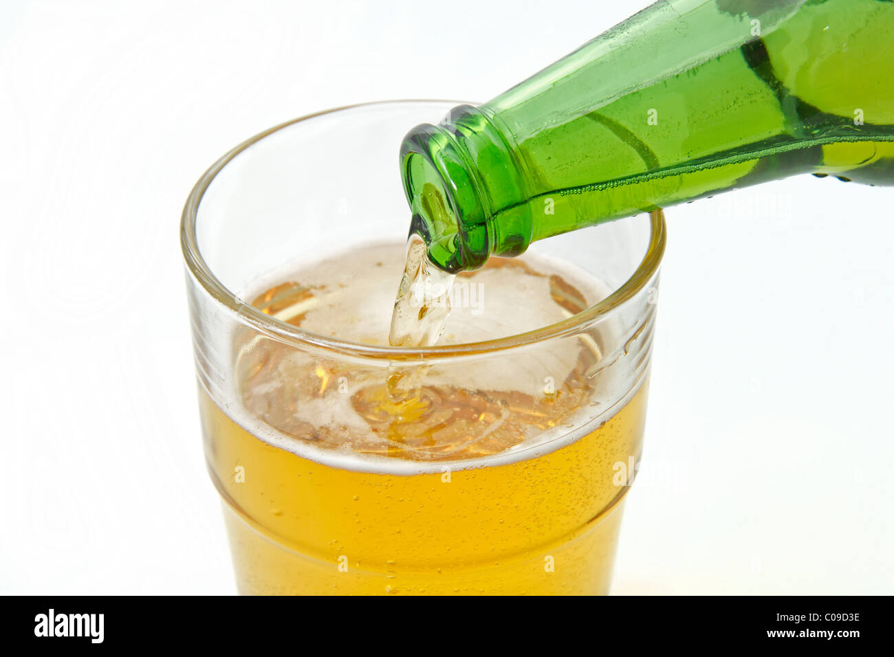 Pouring beer from a green beer bottle into a glass Stock Photo