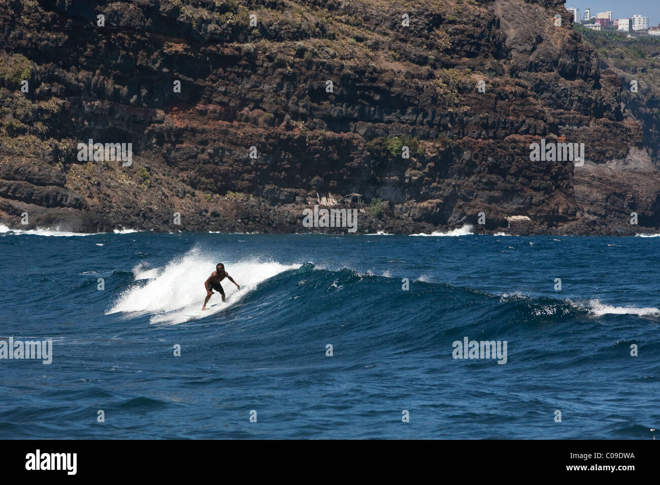Surfer surfing waves by cliffs at Playa Nogales on the east coast La Palma Canary Islands Spain Stock Photo