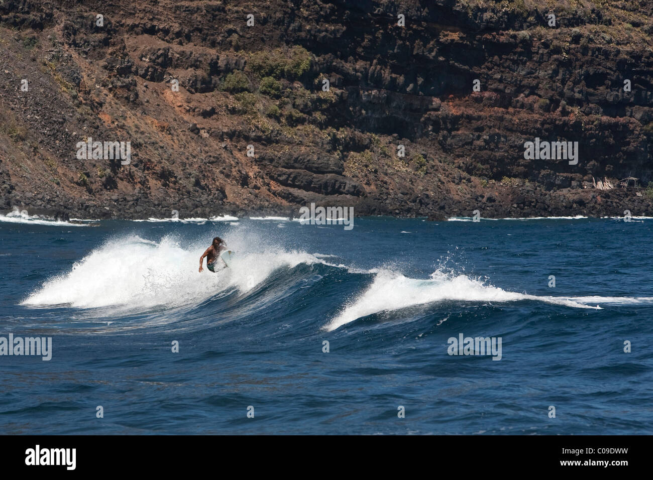 Surfer surfing waves by cliffs at Playa Nogales on the east coast La Palma Canary Islands Spain Stock Photo