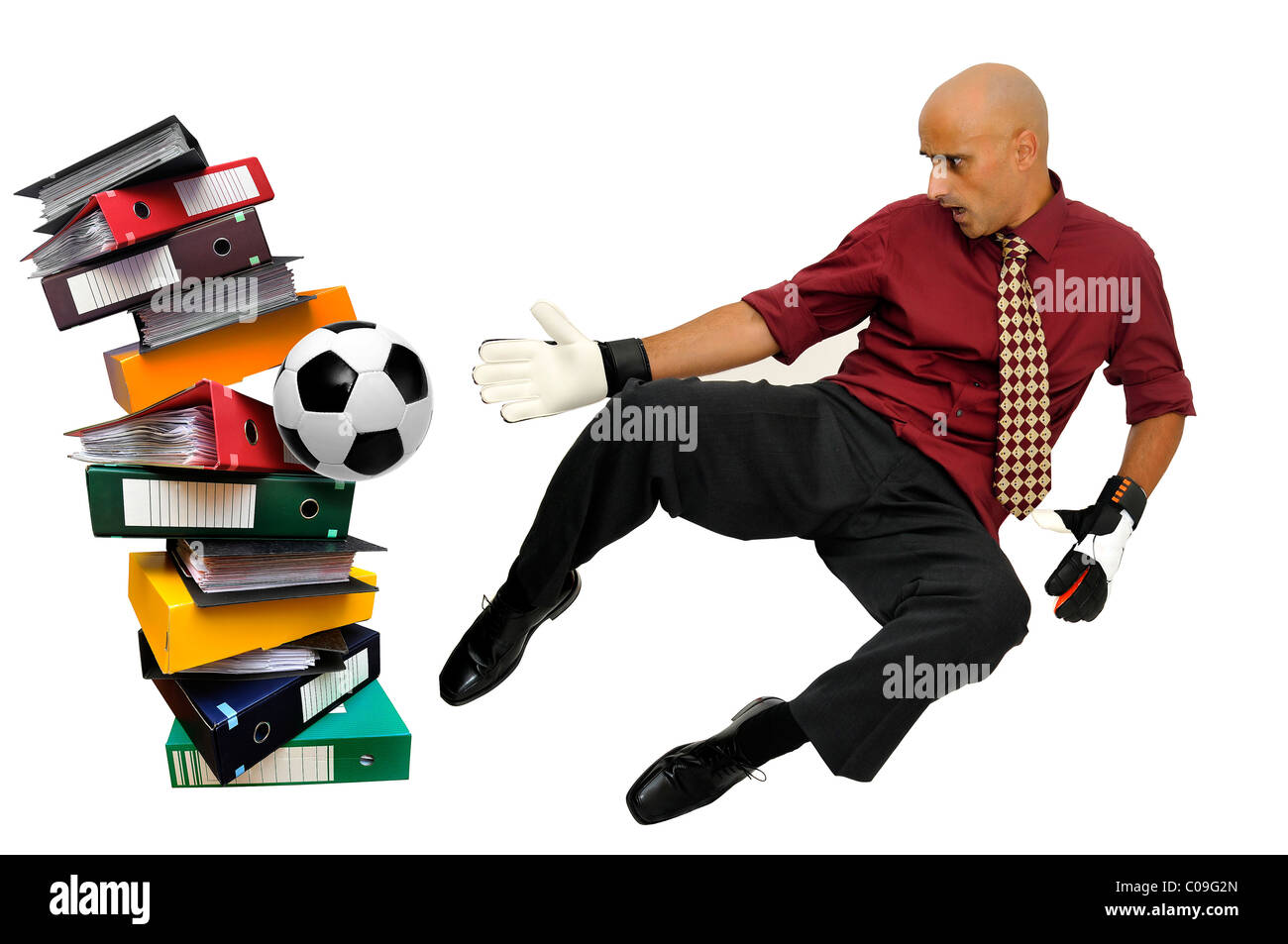 Businessman goalkeeper with gloves and ball in a goal made of files isolated in white Stock Photo